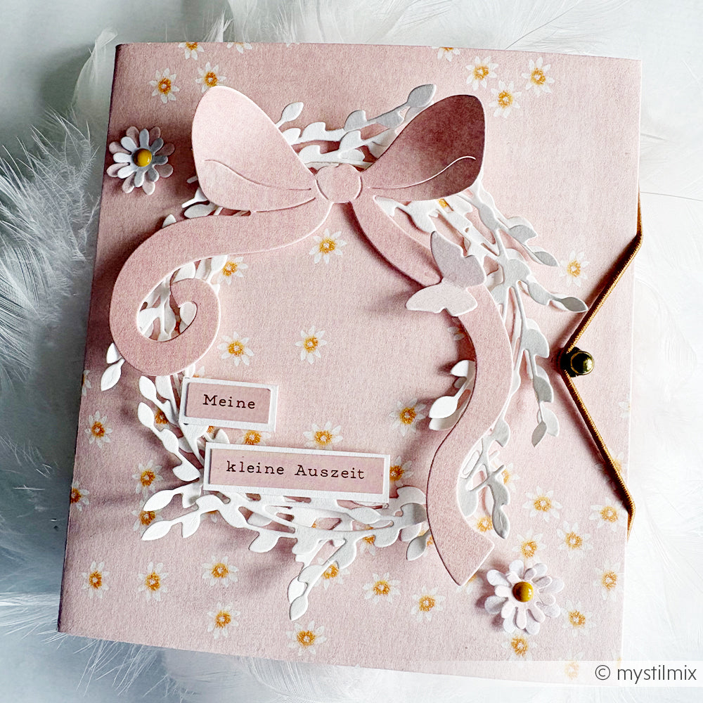 Diese rosafarbene Karte von Alexandra Renke ist aus dem Designpapier Lieblingsblüten auf Altrosa mit einer großen Papierschleife, weißen Blättern, gelben Blüten und dem deutschen Text "Meine kleine Auszeit" gestaltet - ideal für Papierprojekte.