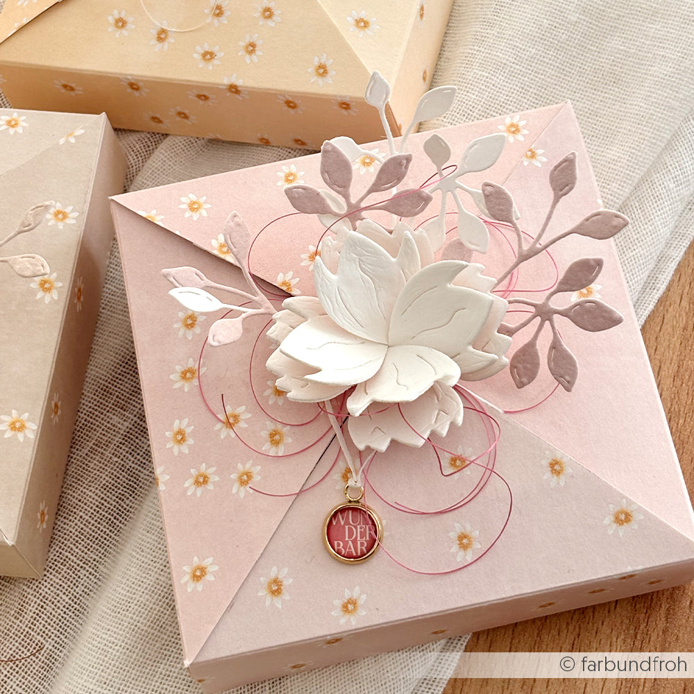 Rosa geblümte Geschenkbox von Alexandra Renke aus Designpapier mit Lieblingsblüten auf Altrosa, verziert mit rosa Kordel und einem goldenen "DU BIST DER HAMMER"-Anhänger.