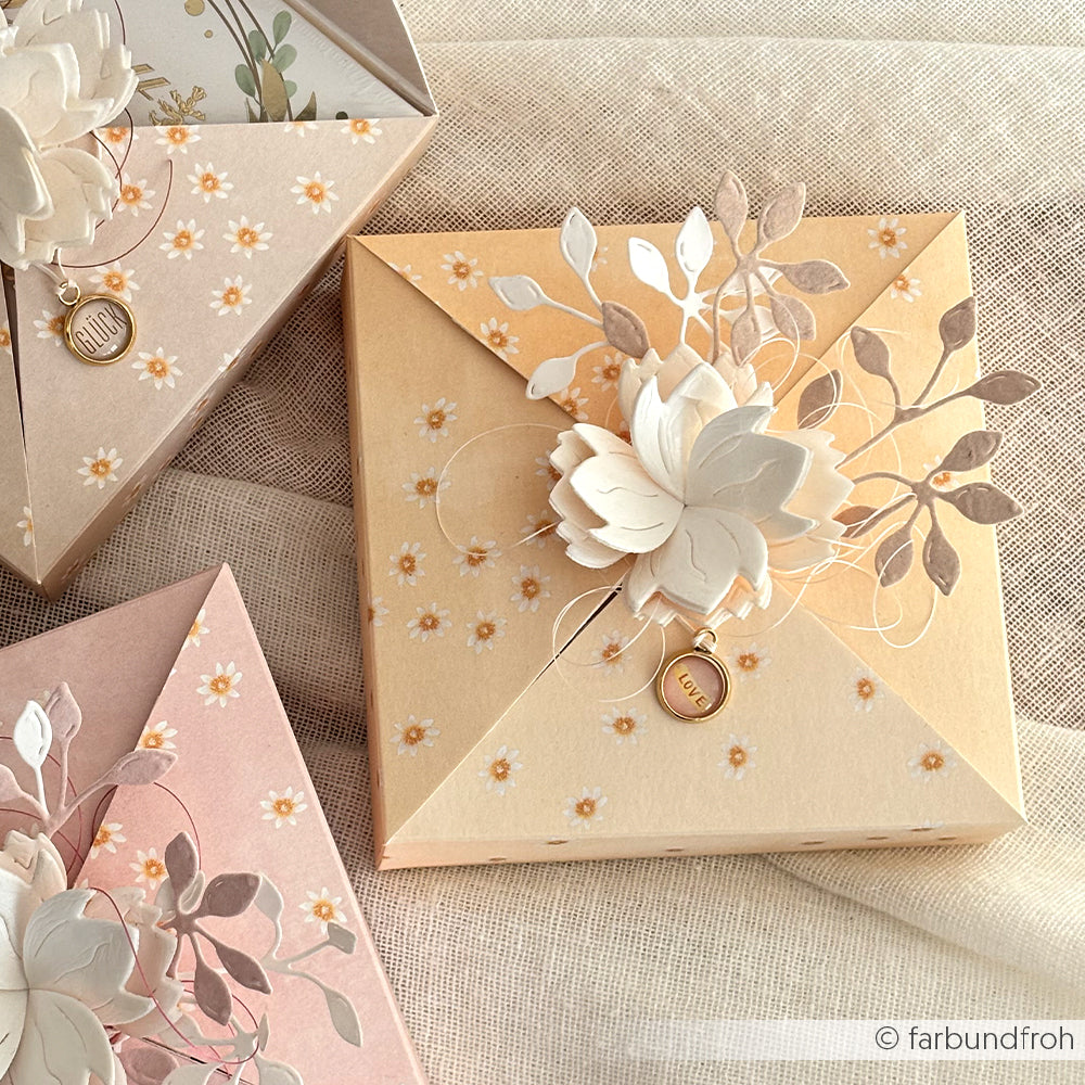 Pastellfarbene, florale Geschenkboxen mit aufwendigen Blüten- und Blattdekorationen aus Alexandra Renke Designpapier Lieblingsblüten auf Warmapricot, arrangiert auf leichtem Stoff - ideal für Ihre nächsten Papierprojekte.