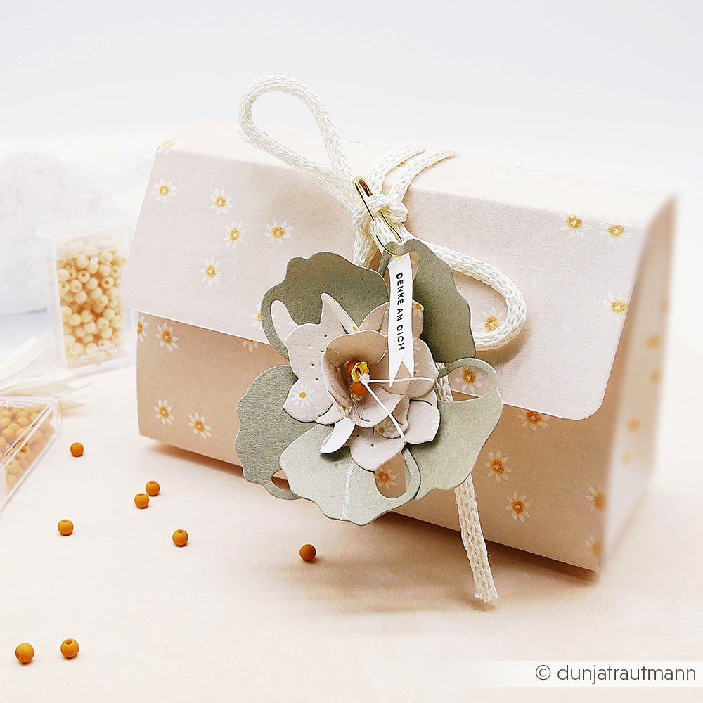 Cremefarbene Designpapier-Geschenkbox von Alexandra Renke, verziert mit einem Blumenanhänger und verstreuten kleinen Perlen - ideal für Lieblingsblüten-Papierprojekte.