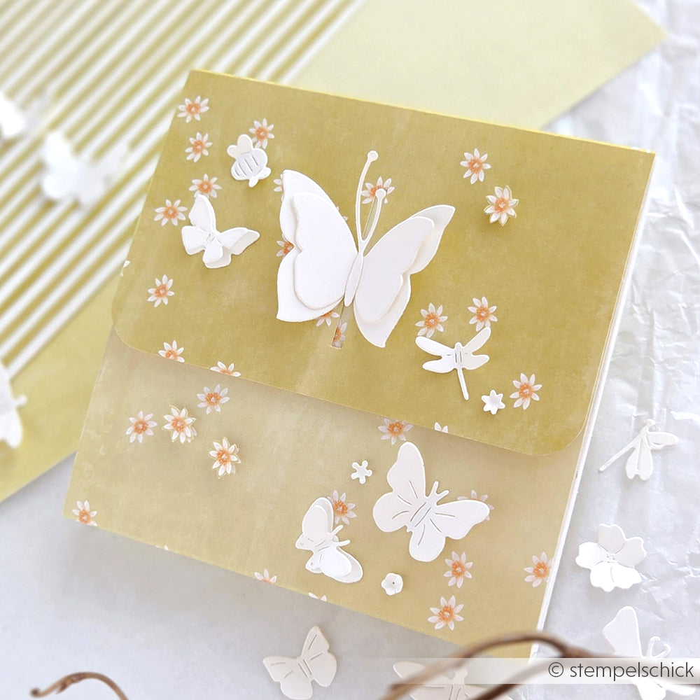 Gelbe Grußkarte von Alexandra Renke mit weißen Schmetterlingen und kleinen orangen Blüten auf Designpapier-ideal für Papierprojekte und auf weißem Untergrund.
