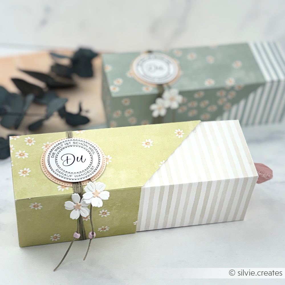 Zwei pastellfarbene Geschenkboxen von Alexandra Renke aus Designpapier mit Lieblingsblüten auf Gelbgrün und kreisrunden Anhängern, die auf einer hellen Fläche platziert sind - perfekte Akzente für Ihre Papierprojekte.