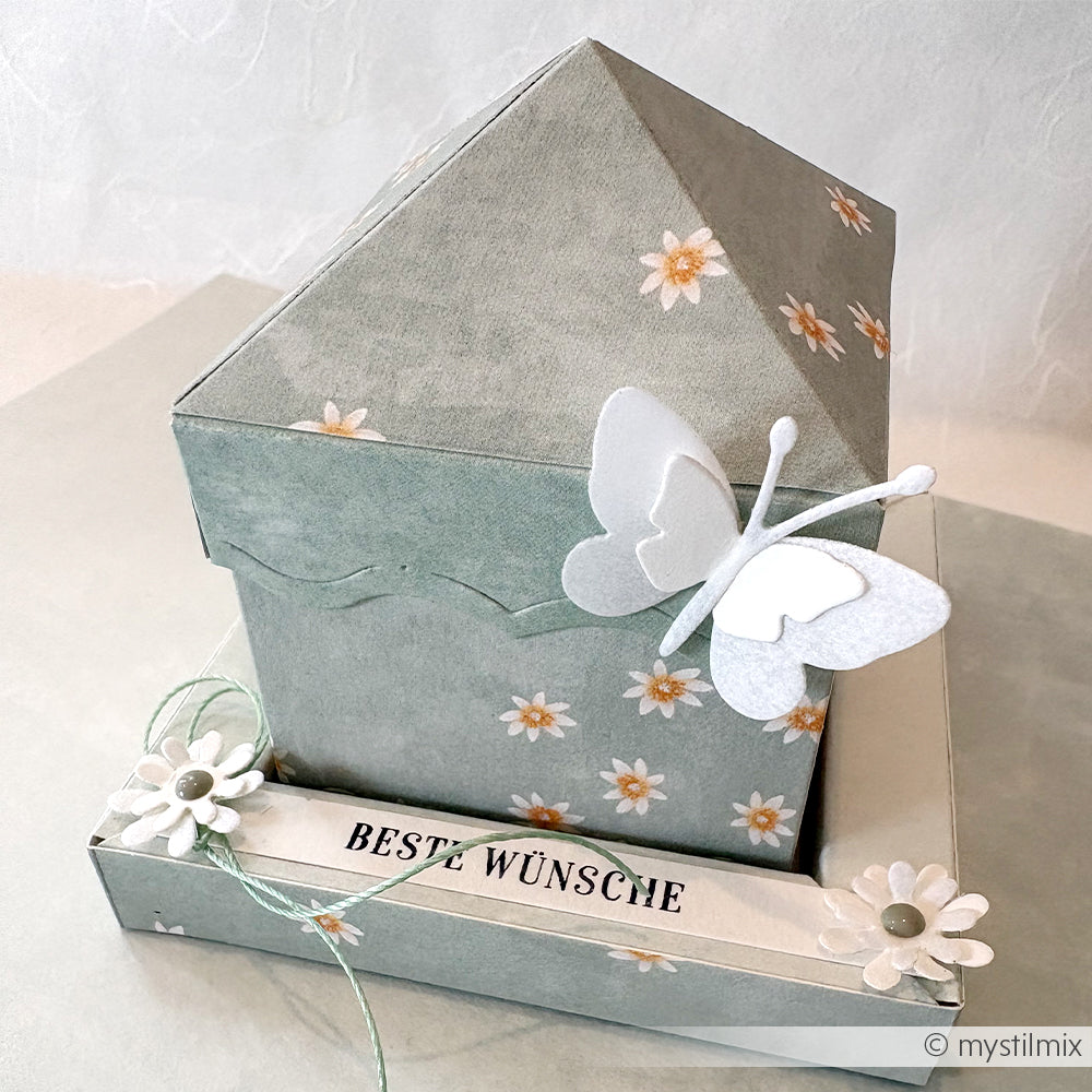 Origami-Geschenkbox aus Alexandra Renke Designpapier mit Blumenmustern-Lieblingsblüten auf Sagegrün-einem weißen Schmetterling und dem Text "BESTE WÜNSCHE" auf dem Boden. Ideal für Papierprojekte und besondere Anlässe.