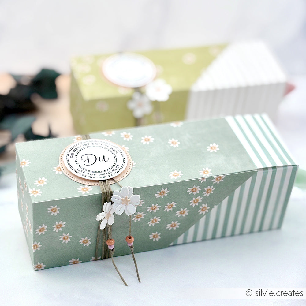 Grün geblümte und gestreifte Geschenkbox aus Alexandra Renke Lieblingsblüten auf Sagegrün Designpapier, veredelt mit einem Du-Anhänger, Bindfaden und zarten weißen Blumen - perfekt für Ihre nächsten Papierprojekte.