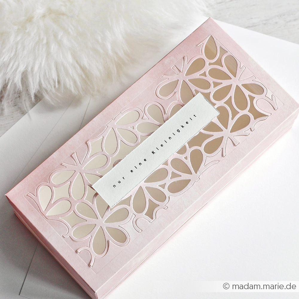 Rosa Schachtel mit floralem Ausschnitt aus Designpapier von Alexandra Renke und weißem Etikett, ausgestellt auf einer weißen Fläche neben flauschigem Stoff - perfekt für Grußkarten oder kreative Papierprojekte.