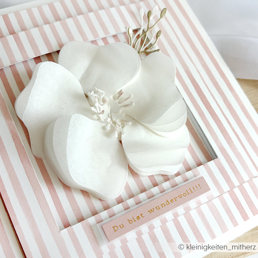 Eine weiße Papierblume ziert eine rosa gestreifte Karte, die mit Alexandra Renke Designpapier Streifen Altrosa gestaltet wurde. Auf der Vorderseite steht "Du bist wundervoll!!!".