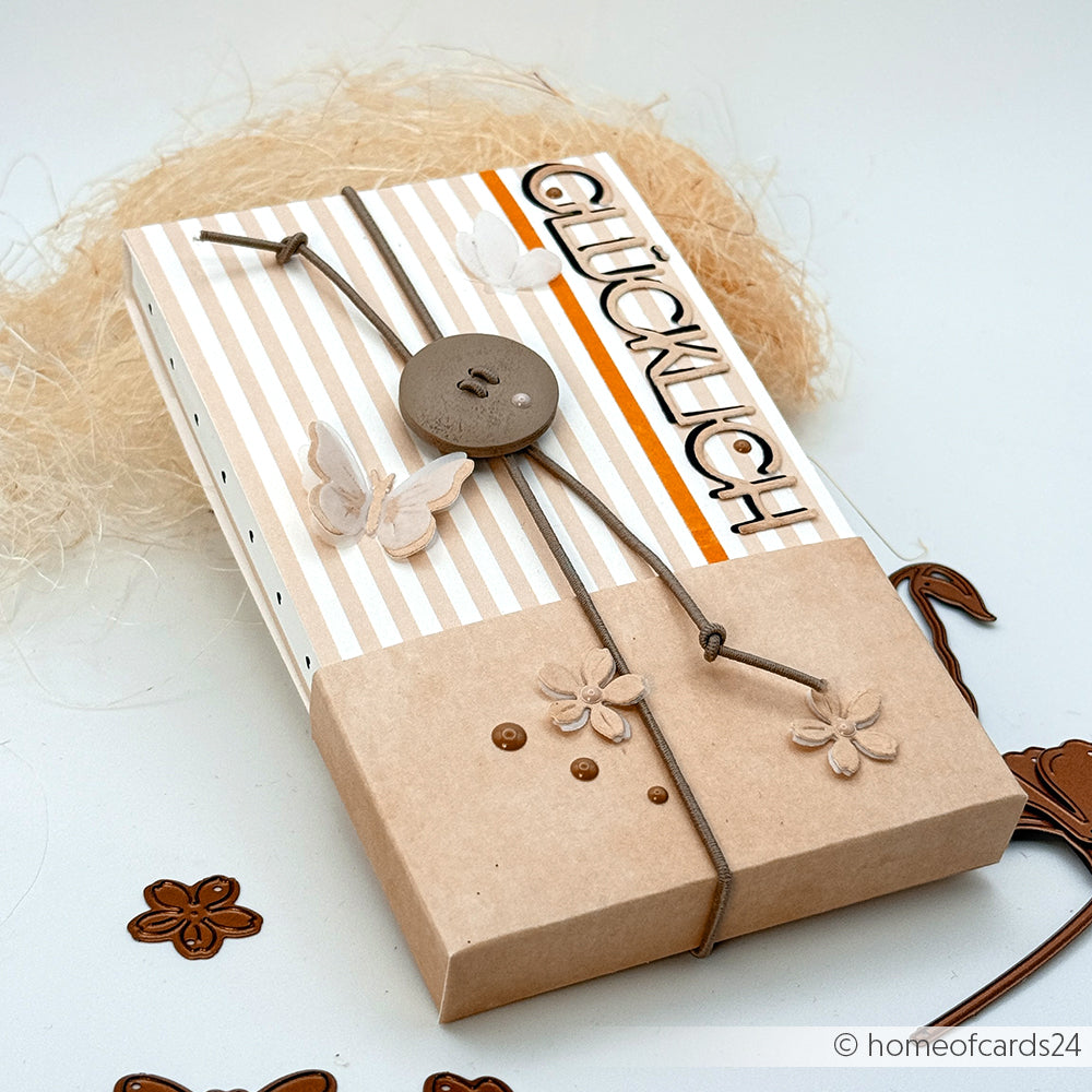 Gestreifte Karte von Alexandra Renke mit GLÜCKLICH-Schriftzug, Ranken, Knöpfen und floralen Akzenten auf beigefarbenem, strukturiertem Hintergrund - ideal für Papierprojekte oder zum Veredeln Ihrer Buchbinderei-Projekte.