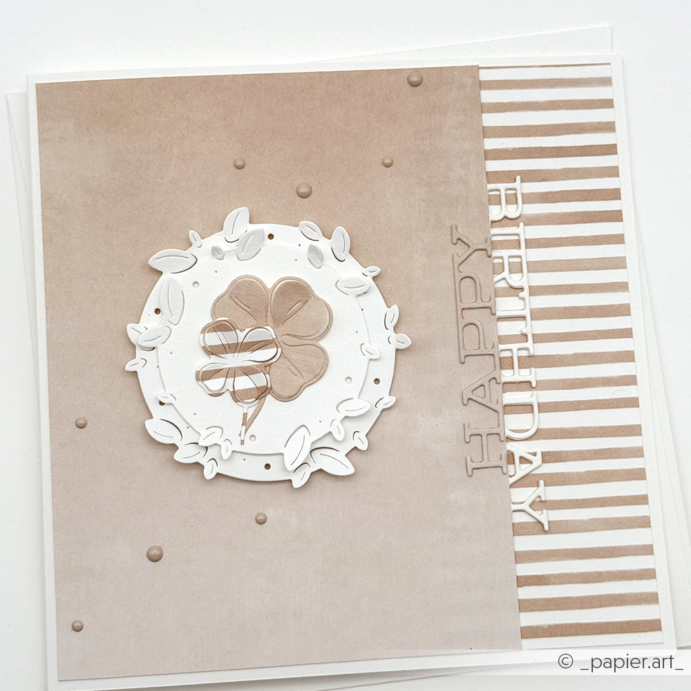 Quadratische Geburtstagskarte von Alexandra Renke mit neutralen Tönen, einem Kleemotiv und "Happy Birthday"-Text auf Puderbeige gestreiftem Designpapier - ideal für Papierprojekte oder Buchbinderei Inspiration.