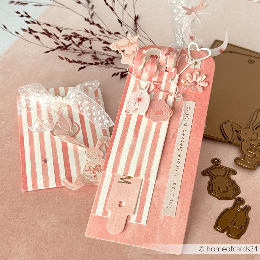 Rosa gestreifte handgefertigte Geschenkanhänger von Alexandra Renke, hergestellt von Designpapier in Streifen Korallrosa, mit Hasen- und Babykleidungsausschnitten, Schleifen und floralen Akzenten - perfekt für Ihre nächsten Papierprojekte.