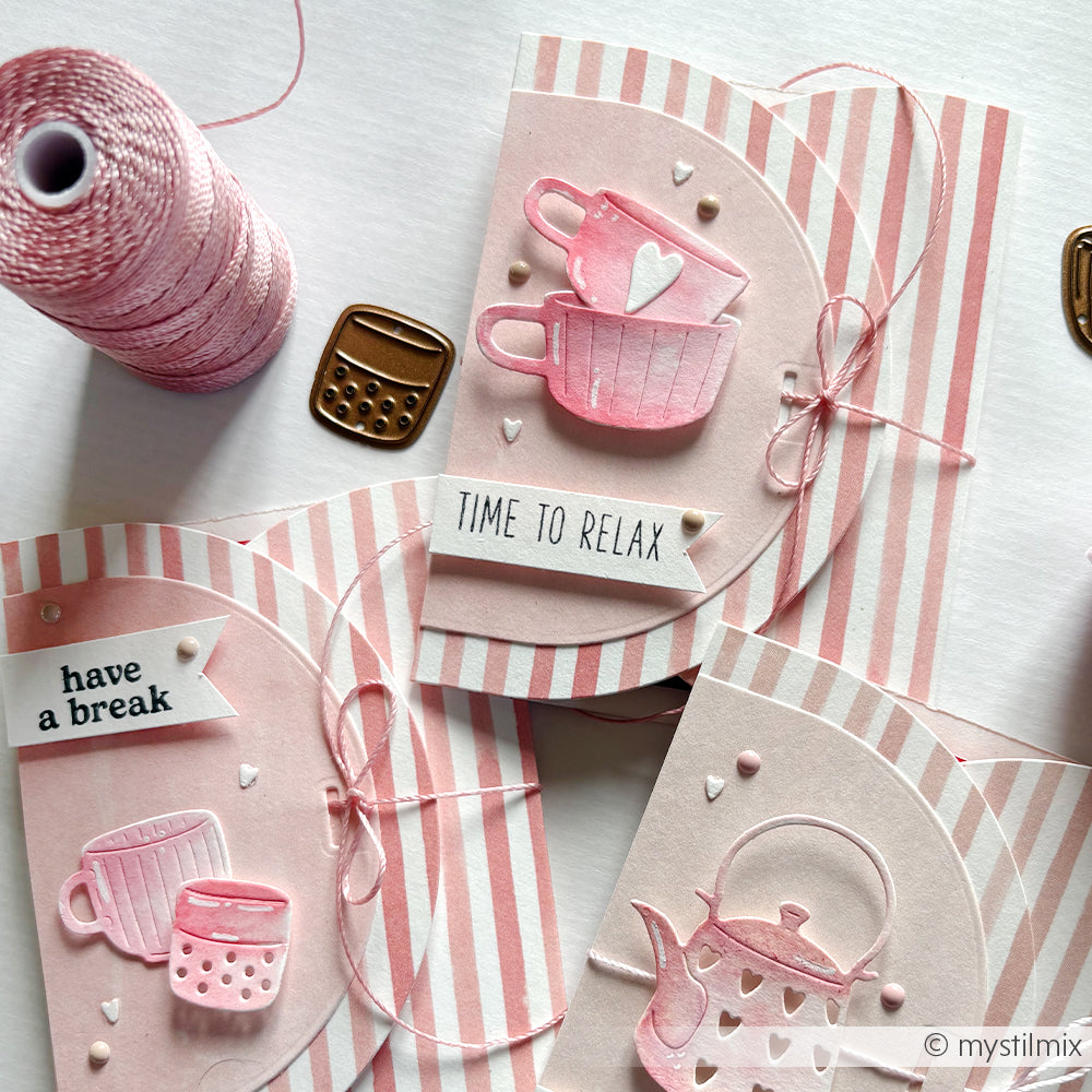 Handgefertigte rosa-weiße Grußkarten von Alexandra Renke mit Teetassen- und Teekannenmotiven auf gestreiftem Korallrosa Designpapier, verziert mit einer Kordel und einem kleinen Taschenrechneranhänger - ideal für einzigartige Papierprojekte.