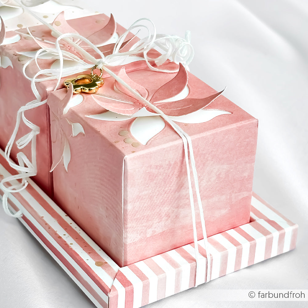 Rosafarbene Geschenkschachteln mit weißem Band und zartem Blumendekor auf Alexandra Renke's Streifen Korallrosa Designpapier - ideal für charmante Papierprojekte und schöne Präsentationen.