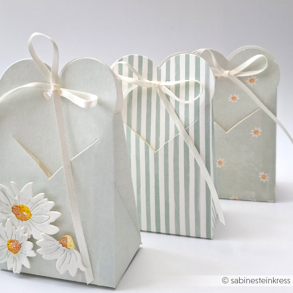 Drei pastellfarbene Geschenktüten mit Schleifenband, gefertigt im Stil von Alexandra Renke mit Designpapier Streifen Jadeblau: eine geblümte, eine gestreifte und eine mit kleinen weißen Blüten. Ideal für Buchbinderei-Fans.