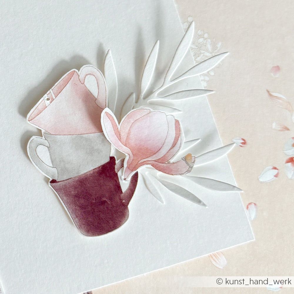 Zarte Papierkunst aus gestapelten Bechern und einer rosa Blume auf Weiß mit dezenten Blattakzenten - die perfekte Inspiration für Alexandra Renke-Fans und Liebhaber von Papierprojekten gleichermaßen.