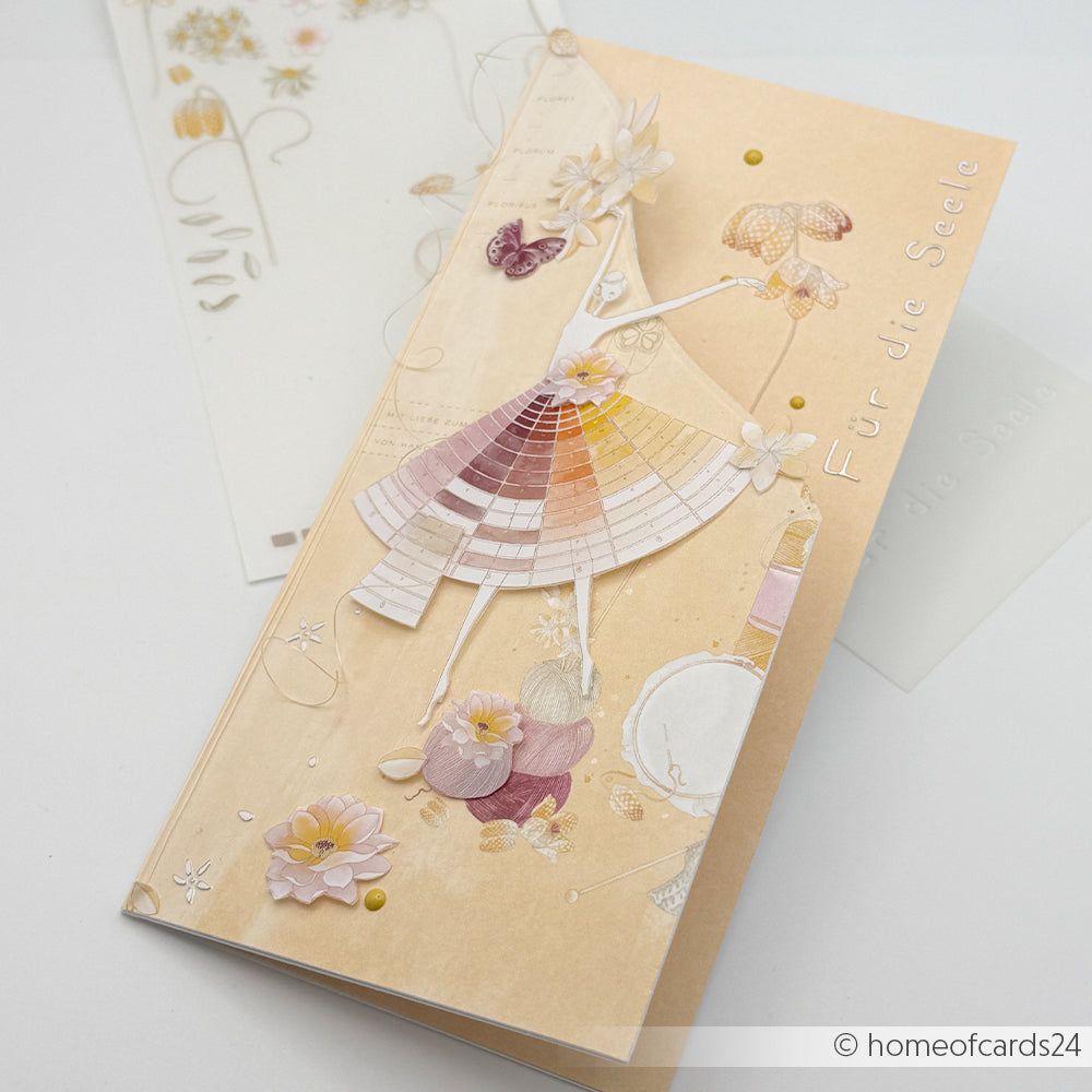 Zarte Grußkarte von Alexandra Renke mit einer stilisierten Frau in einem farbenfrohen Kleid mit floralen Akzenten aus Wolle und der Aufschrift „Für die Seele“ auf Deutsch. Ideal für Bastelprojekte oder als Inspiration für einzigartiges Designpapier.