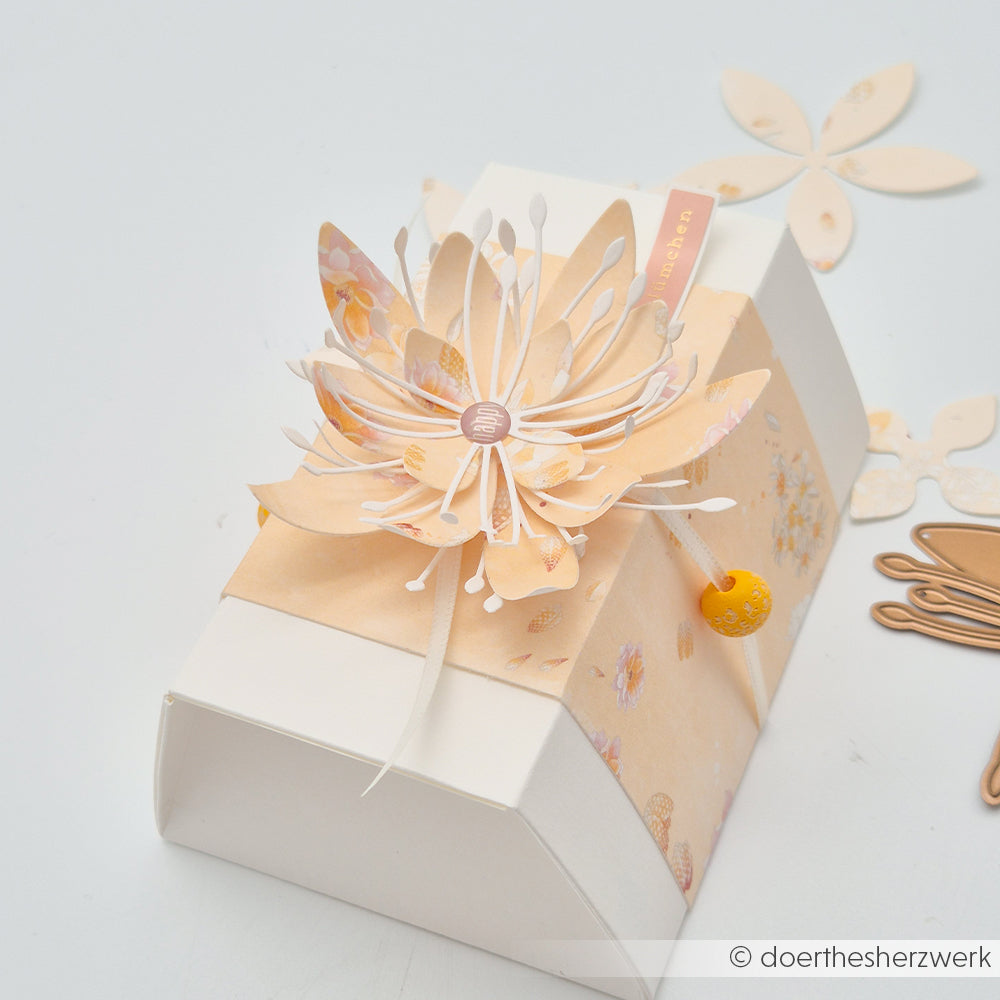 Cremefarbene Geschenkbox von Alexandra Renke, verziert mit einer „Florale“-Blütenkomposition aus pfirsichfarbenem Designpapier und gekrönt von einem kleinen gelben Anhänger.