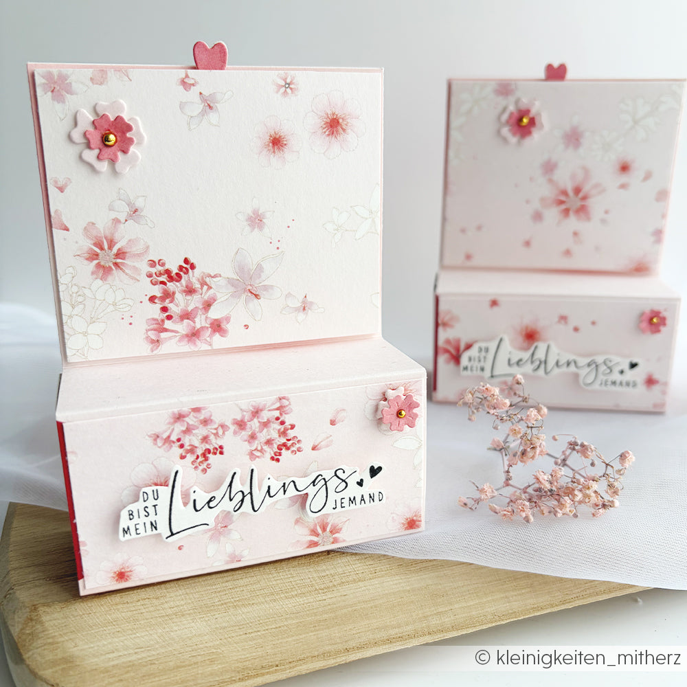 Alexandra Renke: Rosa-weiße Pop-up-Karten mit deutschem Text, aus Designpapier gefertigt und mit Papierherzen und Blumenarrangements verziert. Ideal für Papierprojekte und besondere Anlässe.