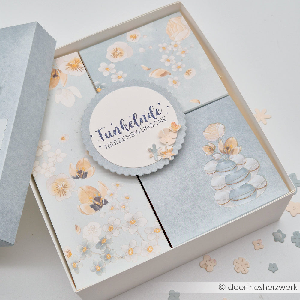 Eine pastellfarbene Geschenkbox mit Blumenmotiv von Alexandra Renke, verziert mit „Herzenswünsche“ auf einem runden Anhänger und zarten floralen Schiffskompositionen im Inneren – perfekt für Ihre nächsten Papierprojekte oder zum Basteln aus exquisitem Designpapier.
