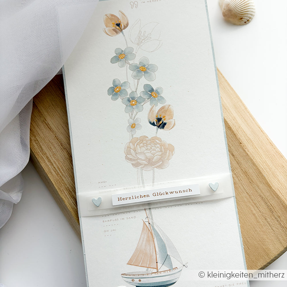 Eine Karte von Alexandra Renke mit pastellfarbenen Blumen und einem Segelboot, hergestellt aus edles Designpapier, enthält "Herzlichen Glückwunsch" auf einem Band.