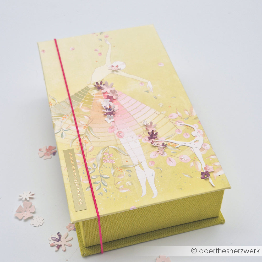 Dekorative gelbe Schachtel von Alexandra Renke mit Ballerina-Motiv, rosa Blumen und rotem Gummiband – ideal für Papierprojekte oder zum Kombinieren mit Akzenten aus dem Designpapier „Florale Garten“.