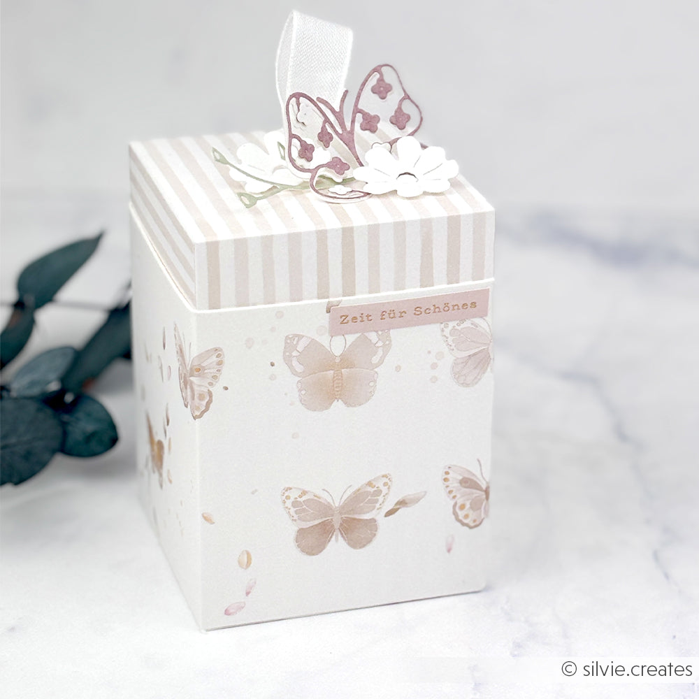 Dekorative Schachtel von Alexandra Renke mit einem floralen Schmetterlingsmuster, einem gestreiften Deckel und Akzenten von „Papierprojekte“ in Form von Papier-Schmetterlingen und Blumenverzierungen auf der Oberseite.