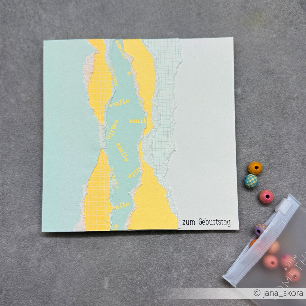 Handgefertigte Geburtstagskarte mit zerrissenem pastellfarbenem Designpapier, einem „Smile“-Text und bunten Perlen in einem kleinen Plastikbeutel – eine reizvolle Wahl für Papierprojekte.