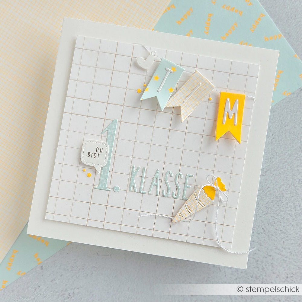 Handgefertigte Karte mit der Aufschrift „1. Klasse“, kariertem Hintergrund, Wimpelkette und einer kleinen Schulkegel-Dekoration aus Papier – perfekt für Papierprojekte und aus hochwertigem Designpapier gefertigt, das für ein farbenfrohes Erscheinungsbild sorgt.