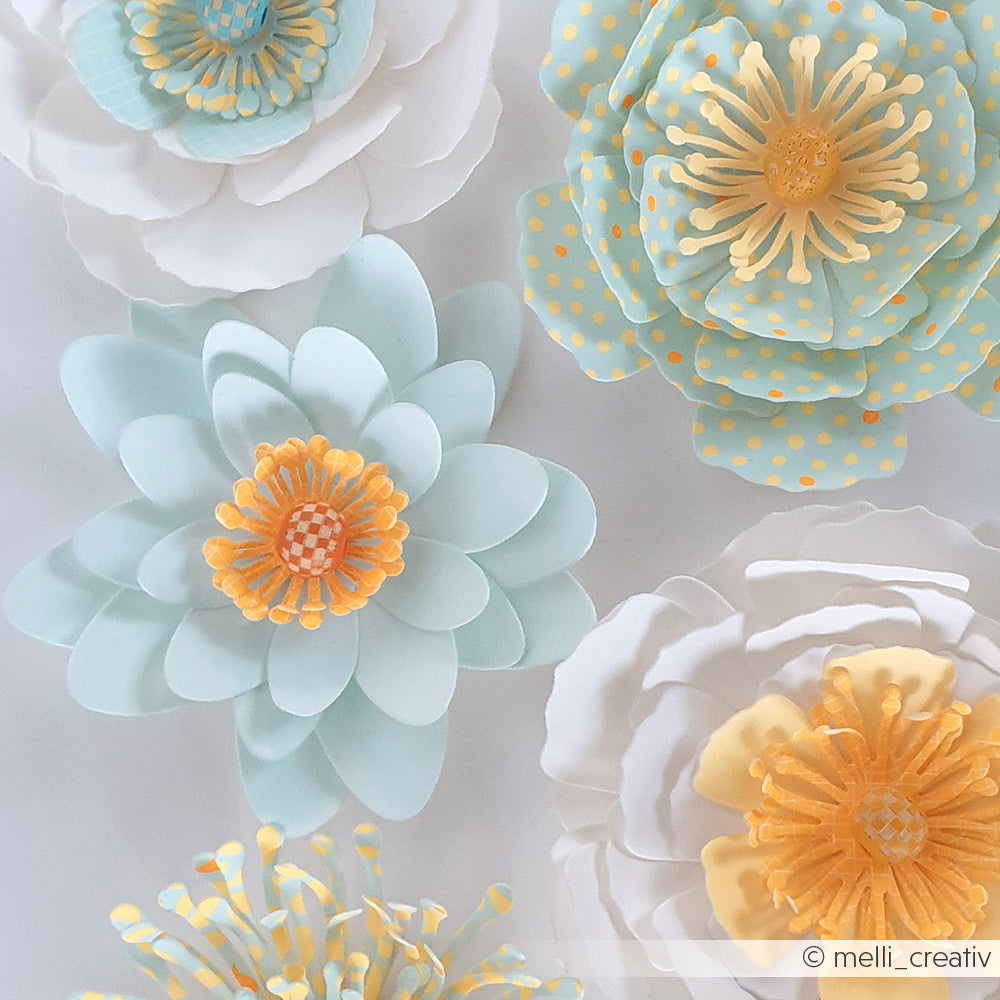 Papierblumen in Pastellfarben mit gelben Blütenmitten und Punkten, arrangiert vor einem hellen Hintergrund aus Designpapier und akzentuiert mit Akzenten in der Farbe „Mimi Summer Special Leuchtend Aqua“.