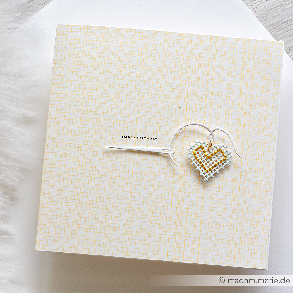 Quadratische Karte mit einem goldenen Herz-Anhänger und der Aufschrift „Happy Birthday“ auf einem dezenten gelben Rasterhintergrund, gefertigt aus Designpapier „Sonnengelb“ – perfekt für fröhliche und farbenfrohe Papierprojekte.