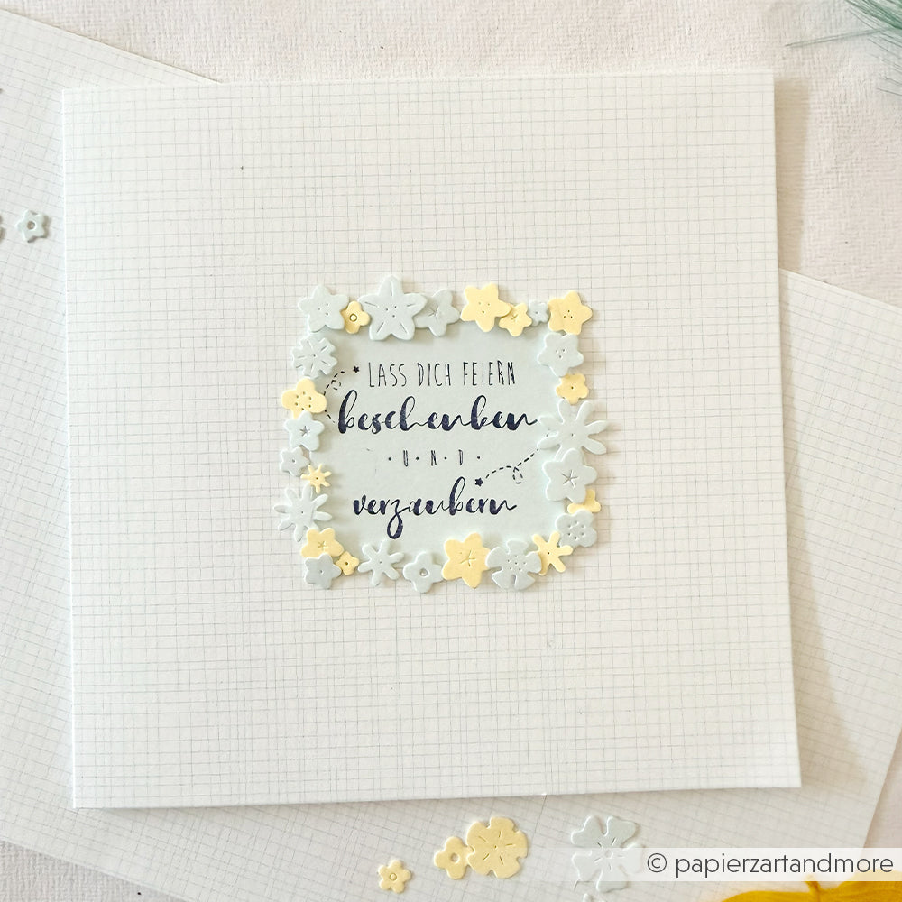 Quadratische Karte mit deutschem Text, umrahmt von kleinen pastellfarbenen Papierblumen auf einem karierten Hintergrund – die perfekte Inspiration für Ihre nächsten Papierprojekte oder um Ihr Lieblings-Designpapier in Szene zu setzen.