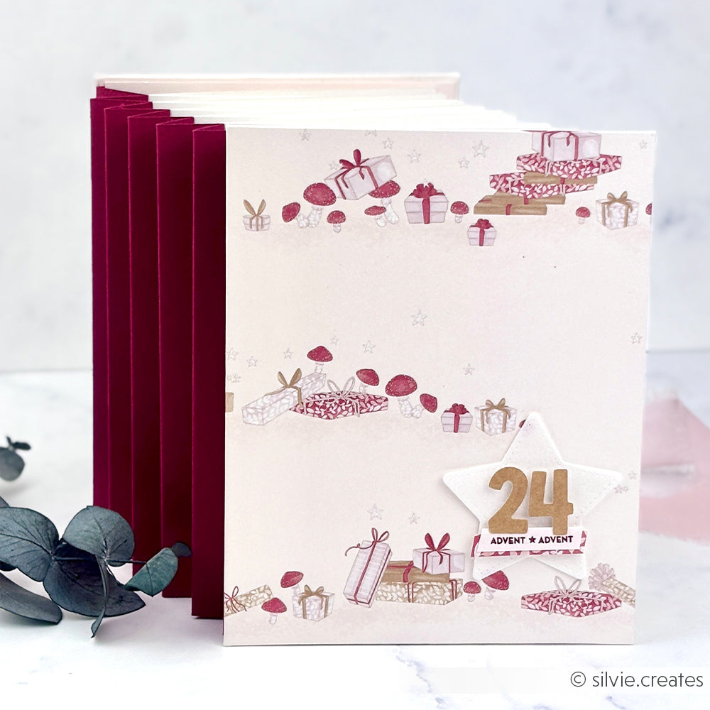 Adventskalender im Ziehharmonika-Stil mit Weihnachtsgeschenken, Pilzillustrationen und Designpapier.