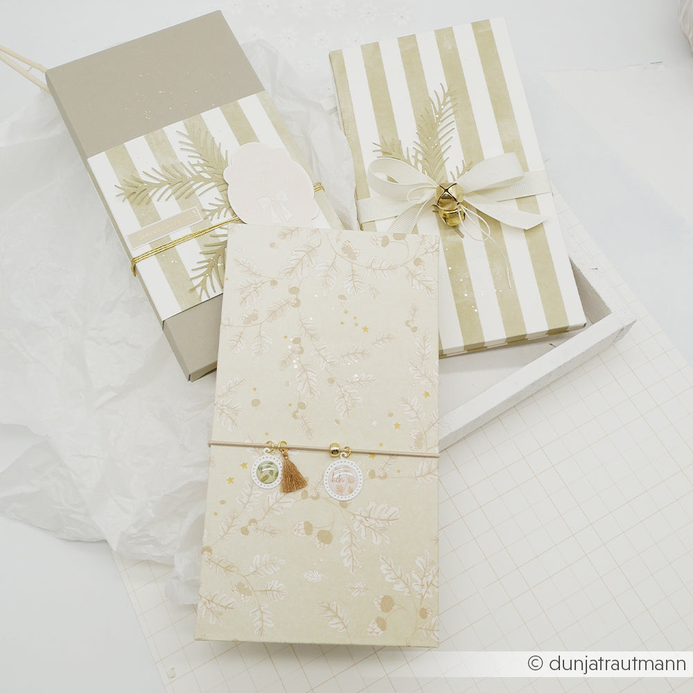 Drei in Designpapier verpackte Geschenke mit Schleifen in einer weißen Schale.