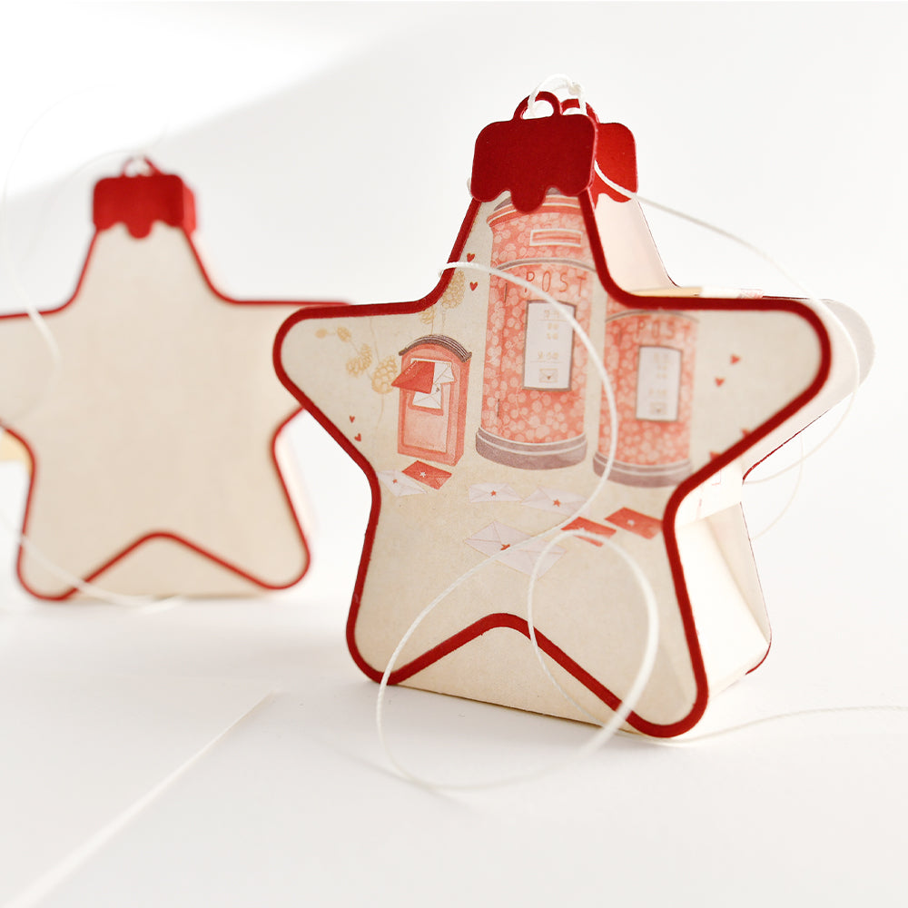 Zwei sternförmige Ornamente, verziert mit Weihnachtspost-Motiven von roten Briefkästen.