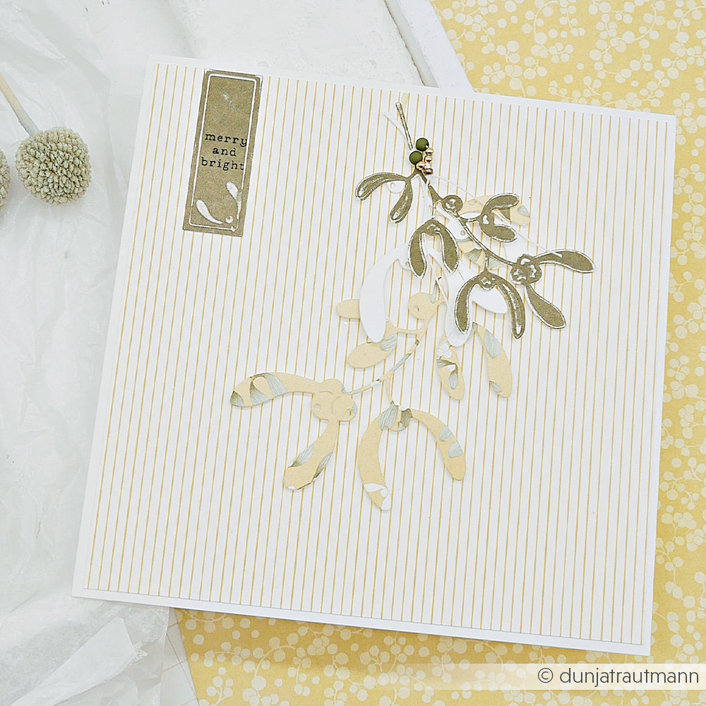 Handgefertigte Weihnachtskarte aus Designpapier mit einem Mistelzweig und dem Schriftzug Merry and Bright.
