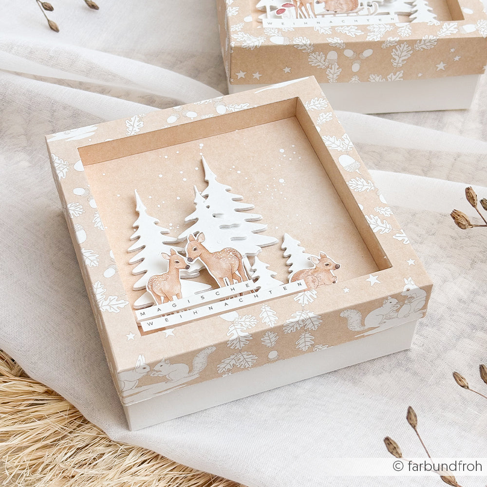 Dekorative Geschenkbox mit Papierbasteleien, darunter 3D-Rehe und Tannenbäume.