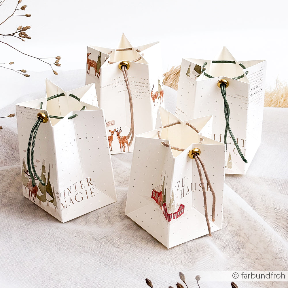 Vier sternförmige Geschenktüten aus weißem Papier mit Winterstadt-Motiven und Winterillustrationen.