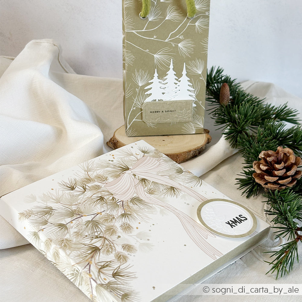 Eine Geschenktüte und eine quadratische Geschenkbox aus Designpapier mit Kiefernmotiven und Weihnachtsetiketten.