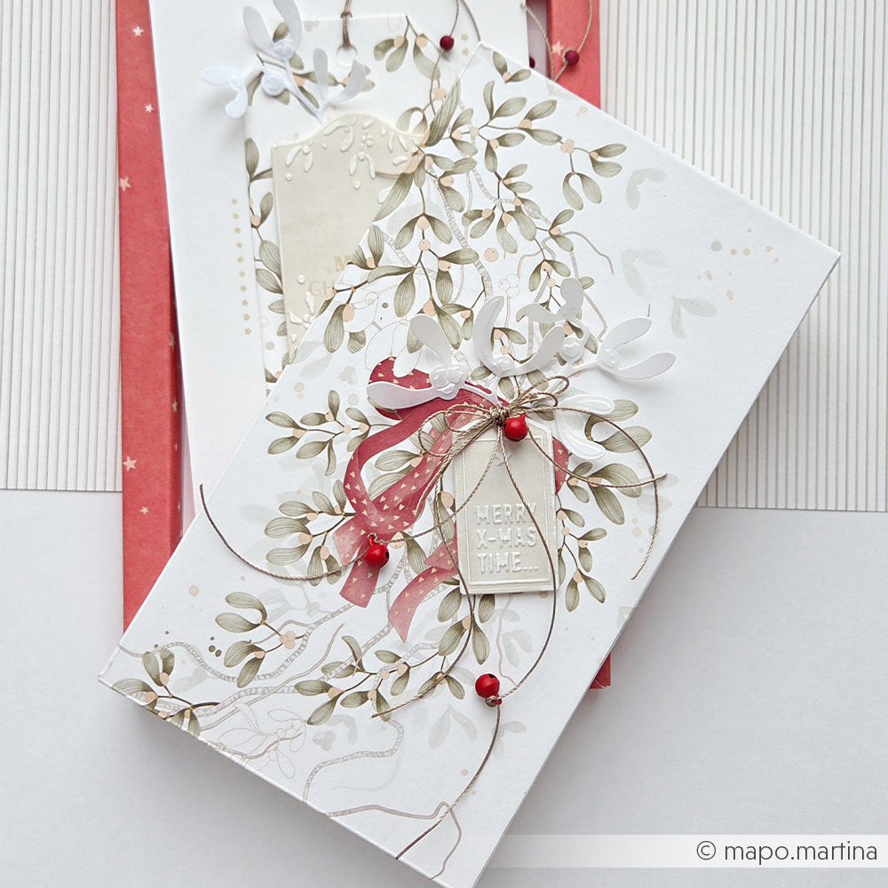 Zwei weiße Geschenkboxen, verpackt in Designpapier mit Mistelzweigen und einem Anhänger mit der Aufschrift Merry X-mas time.