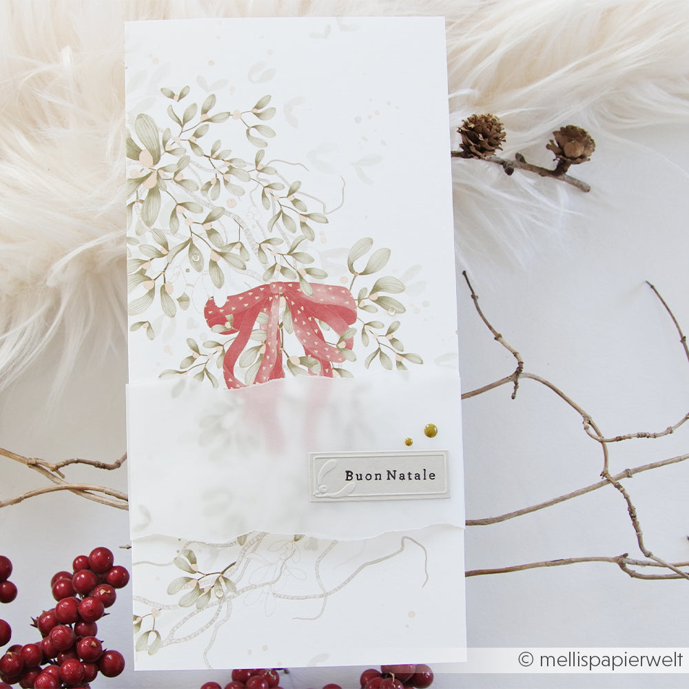 Hohe Weihnachtskarte mit Mistelzweig, einem roten Band und einem Buon Natale-Anhänger auf Designpapier.