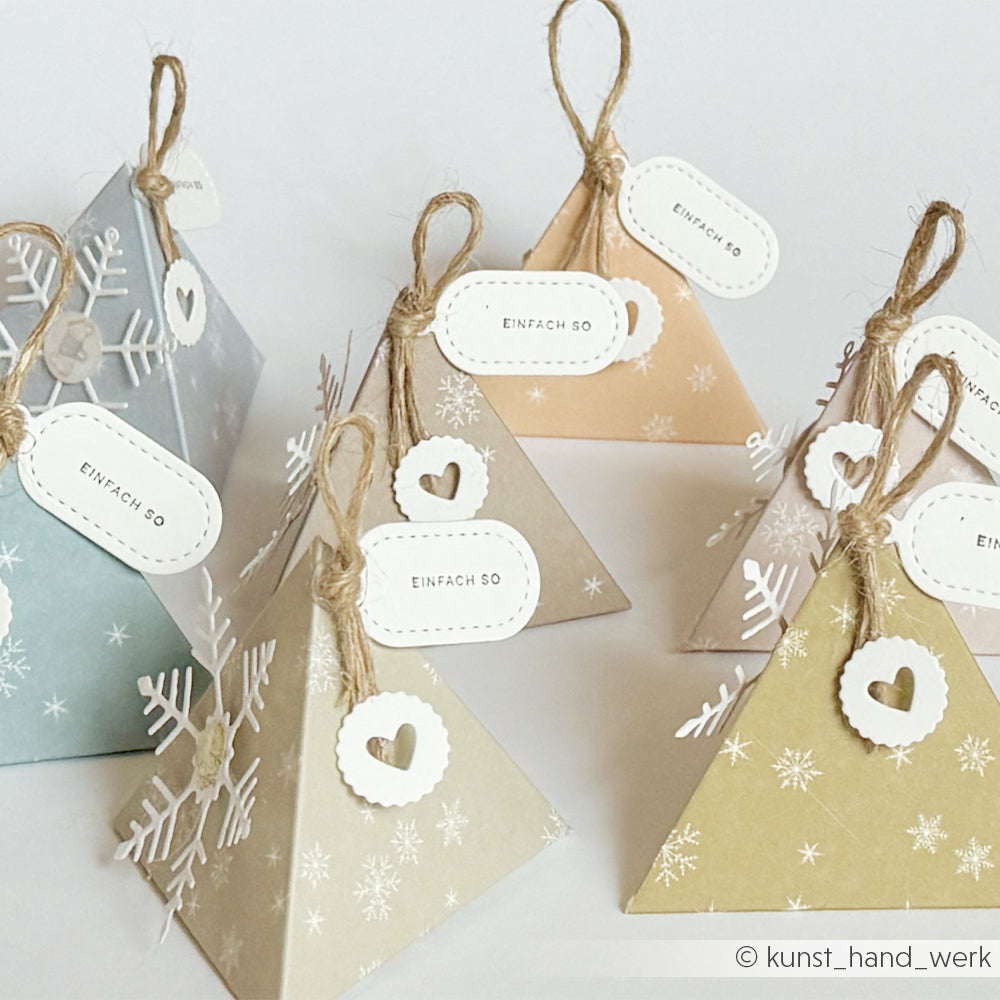 Pyramidenförmige Geschenkboxen in zartem Grün mit Schneeflocken und Anhängern mit der Aufschrift EINFACH SO.