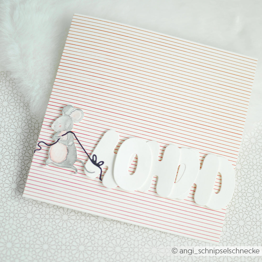 Ein rot gestreiftes Designpapier, auf dem eine kleine Maus die ausgeschnittenen Buchstaben MOMO zieht.