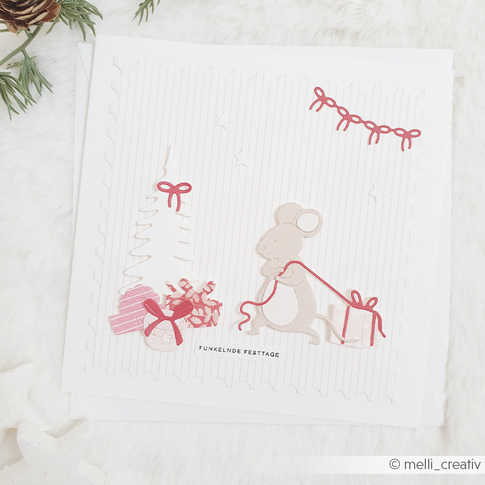 Eine ausgestanzte Maus, die ein Geschenk neben einem Weihnachtsbaum aus Papier auf Designpapier Zarte Streifen Rosa hinter sich herzieht.
