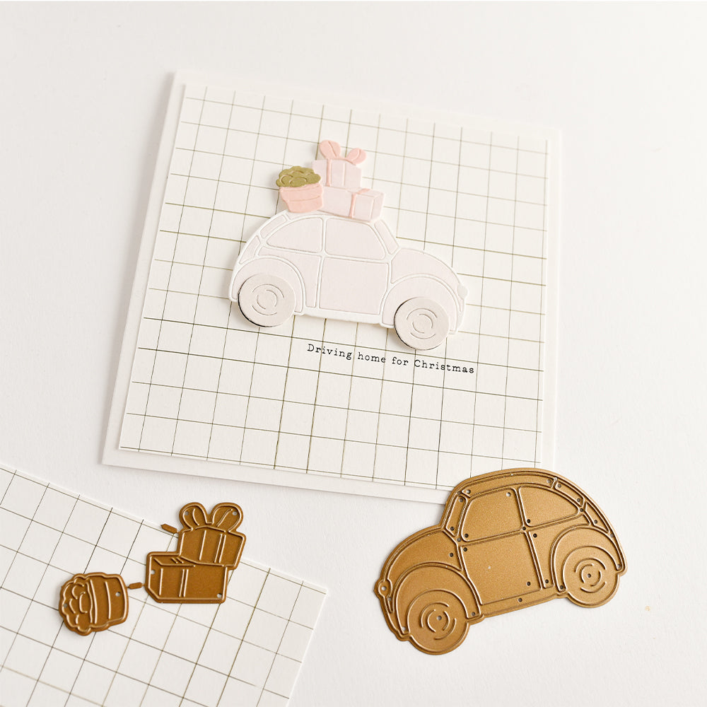 Eine Karte mit einem ausgestanzten Auto, das Geschenke transportiert, und dem Schriftzug „Driving home for Christmas“ sowie passenden Stanzformen aus Metall – ideal für Papierbastelprojekte und die Buchbinderei.