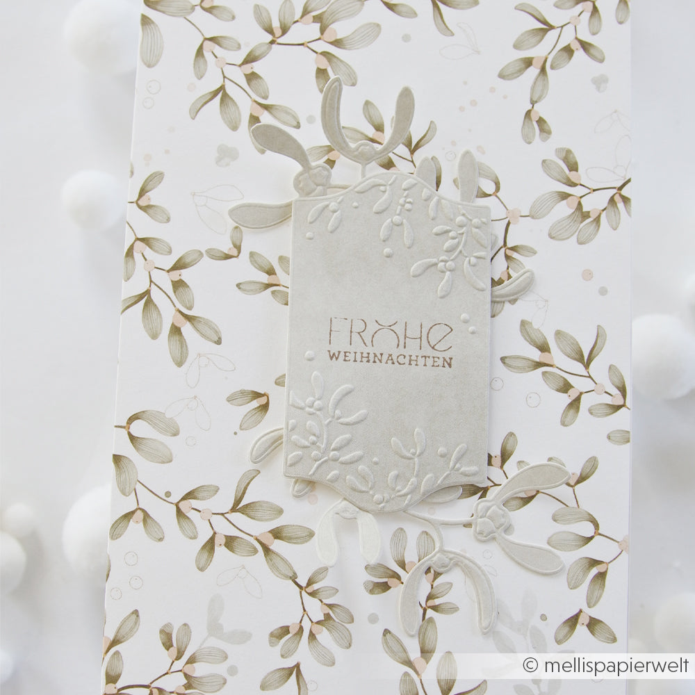 Geschenkanhänger mit geprägtem Mistelzweig und dem Schriftzug FROHE WEIHNACHTEN auf Designpapier von Mimi Aschgrün.