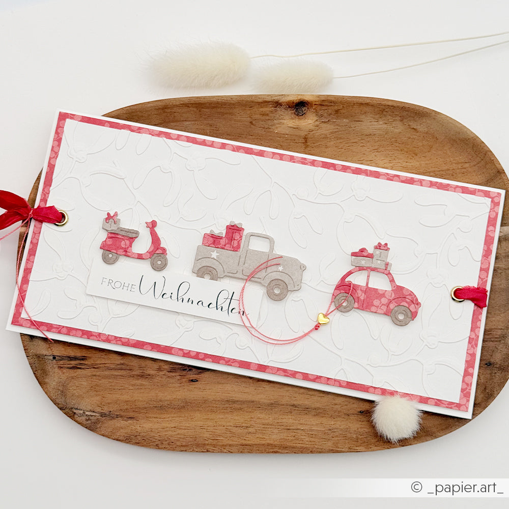 Handgefertigte Weihnachtskarte auf Premiumrot-Papier mit einem Roller, einem Lkw und einem Auto, die Geschenke transportieren.