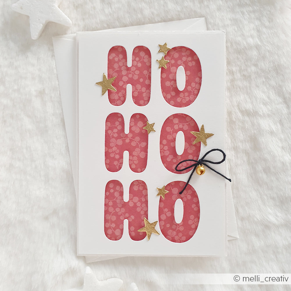 Weihnachtskarte mit HO HO HO-Ausschnitten und goldenen Sternen, gefertigt aus hochwertigem Designpapier.