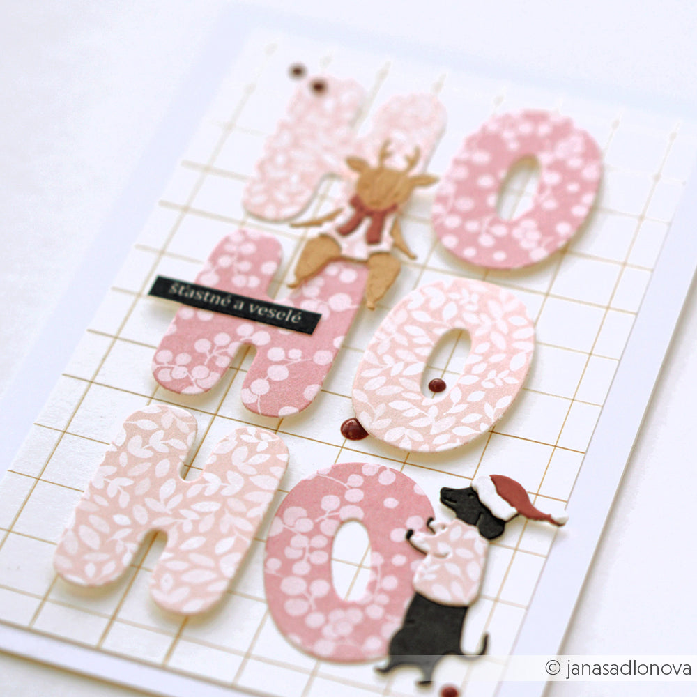 Handgefertigte Karte mit der Aufschrift HO HO HO aus rosa Designpapier-Buchstaben, einem Rentier und einem Weihnachtsmann-Hund.