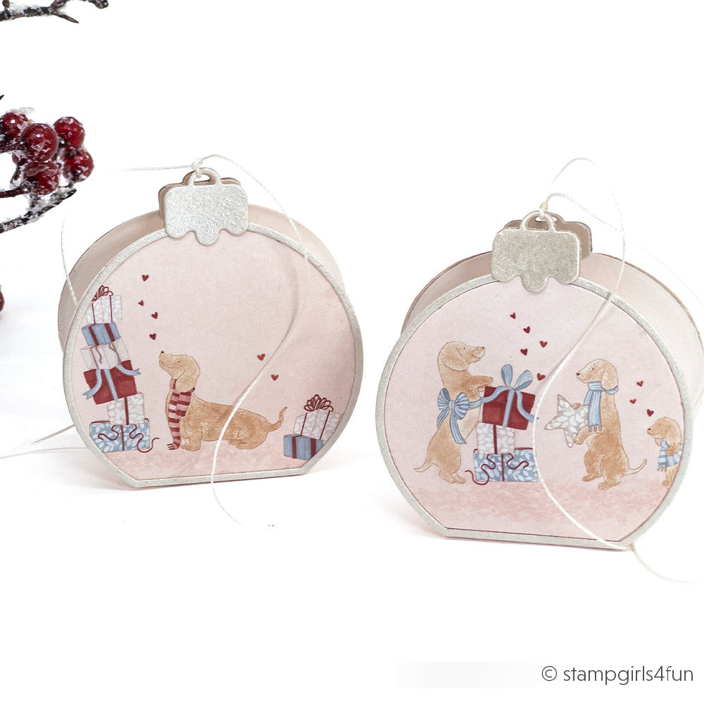 Zwei flache, runde Weihnachtsanhänger mit Motiven von Dackeln und Geschenken – ideal für Bastelprojekte aus Papier.