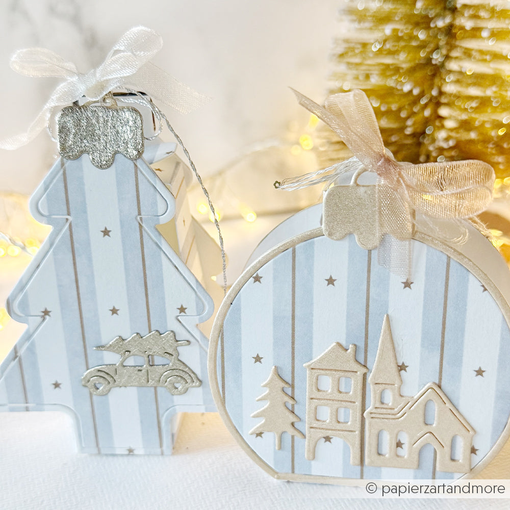 Zwei hellblaue, mit Wasserfarben gestreifte Geschenkboxen in Form eines Weihnachtsbaums und einer runden Weihnachtskugel.