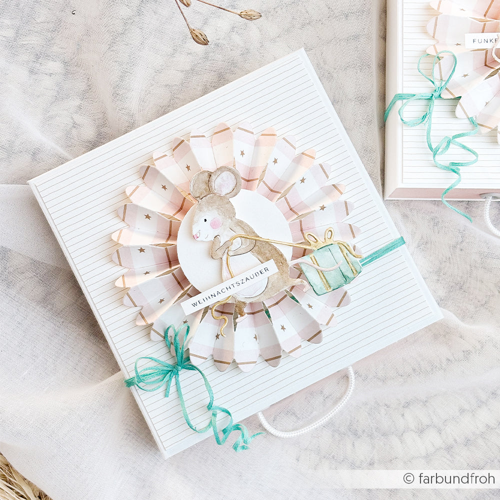 Geschenkbox mit einer Papierrosette mit Mausmotiv und der Aufschrift WEIHNACHTSZAUDER auf gestreiftem Designpapier.