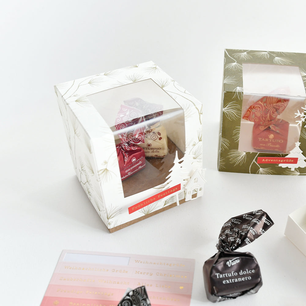 Zwei Geschenkboxen mit verpackten Pralinen und Weihnachtsaufklebern für Papierprojekte.